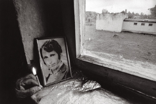 φωτογραφία νεκρού άνδρα δίπλα σε παράθυρο και ένα καντήλι αναμμένο