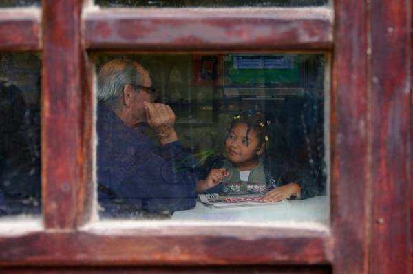 μέσα απο ένα παράθυρο ένας κύριος μιλά με ένα αφροαμερικάνικο κορίτσι που κρατά μία εφημερίδα