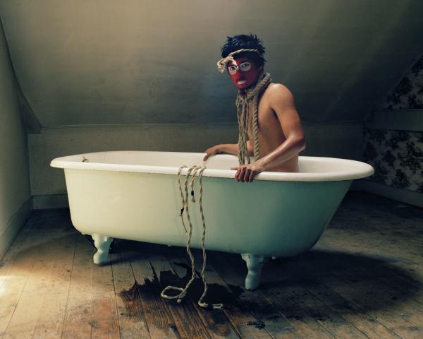 άνδρας με βαμένο πρόσωπο και σχοινί στο λαιμό μέσα σε μπανιέρα