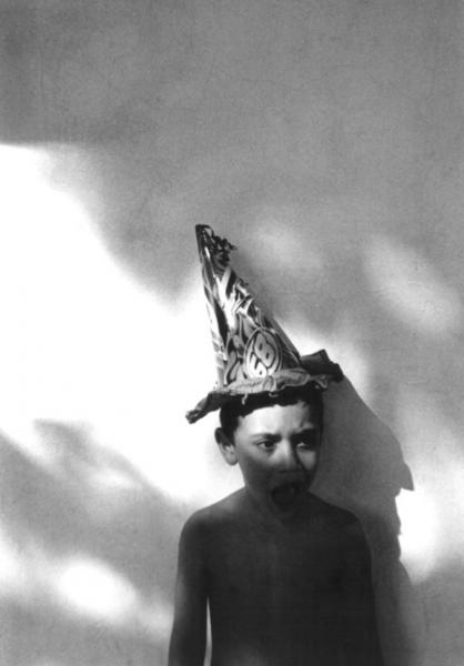 ασπρόμαυρη φωτογραφία, παιδί στέκεται σε τοίχο φορώντας ένα μεγάλο καπέλο