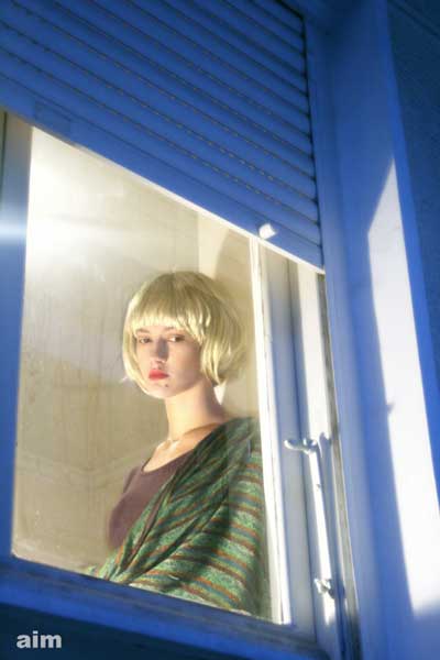ξανθιά γυναίκα κοιτάει από ένα παράθυρο