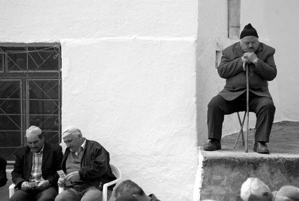 ασπρόμαυρη φωτογραφία / ηλικιωμένοι άνδρες κάθονται / ένας απο αυτούς στηρίζετια σκεφτικός στο μπαστούνι του