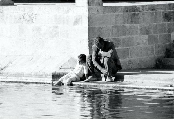 ασπρόμαυρη φωτογραφία, δύο άνδρες καθισμένη σε μια πλατεία, ο ένας έχει τα πόδια στο νερό