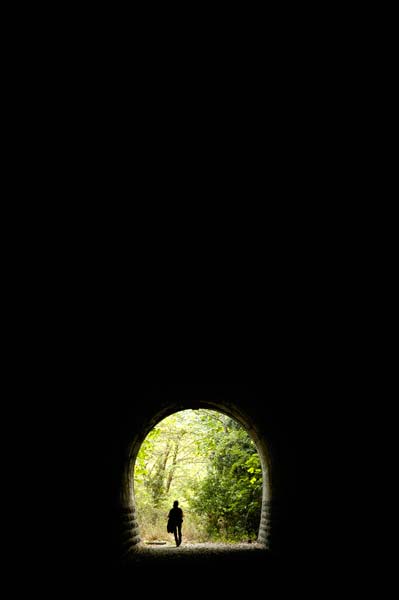 γυναίκα περπατά σε ένα τούνελ που βγάζει σε δάσος