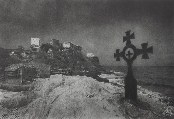 σταυρός πάνω σε βράχο, δίπλα απο τη θάλασσα, στο βάθος ψηλά μοναστήρια του Αγίου Όρους