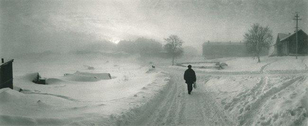 μαυροφορεμένος άνθρωπος περπατά σε ένα χιονισμένο τοπίο