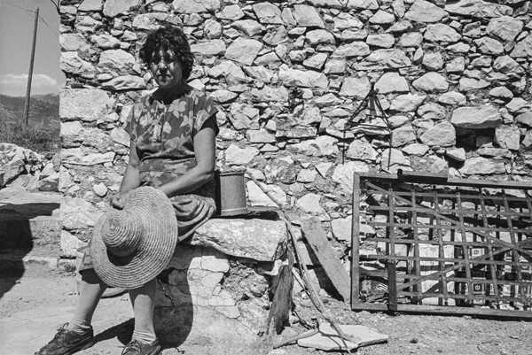 γυναίκα της Μάνης καθισμένη σε πέτρινο πεζούλι