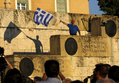 ένας άνδρας κρατά την ελληνική σημαία στο Σύνταγμα