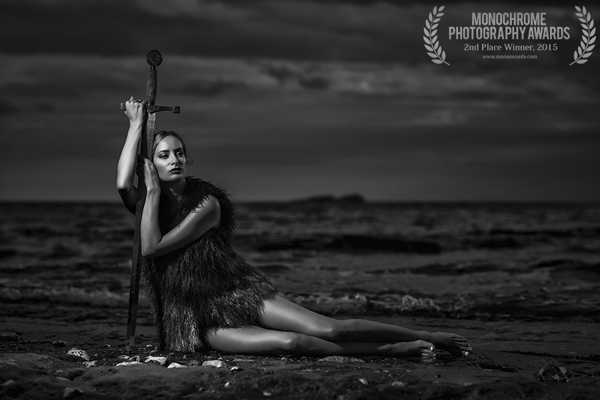 γυναίκα καθισμένη στην παραλία ακουμπά και στηρίζει το σώμα της σε ένα σπαθί