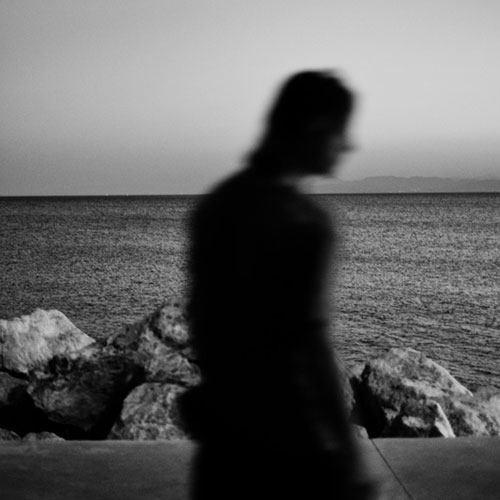 ασπρόμαυρη φωτογραφίας ενός άνδρα γυρισμένου πλάτη και με φόντο τη θάλασσα