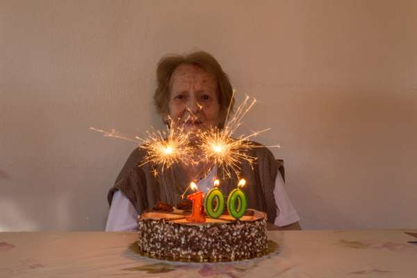 Ηλικιωμένη γυναίκα μπροστά σε τούρτα γενεθλίων σβήνει τα 100 της κεράκια