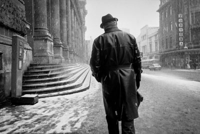 άντρας ντυμένος στα μαύρα προχωράει σε χιονισμένο δρόμο της κεντρικής Ευρώπης