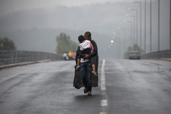 Syrian refugee kisses his daughter as he walks through a rainstorm towards Greece's border with FYROM, near the Greek village of Idomeni