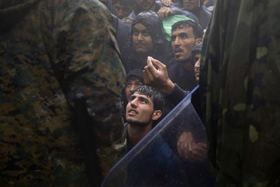 Migrants and refugees beg FYROM policemen to allow passage to cross the border from Greece into FYROM during a rainstorm, near the Greek village of Idomeni