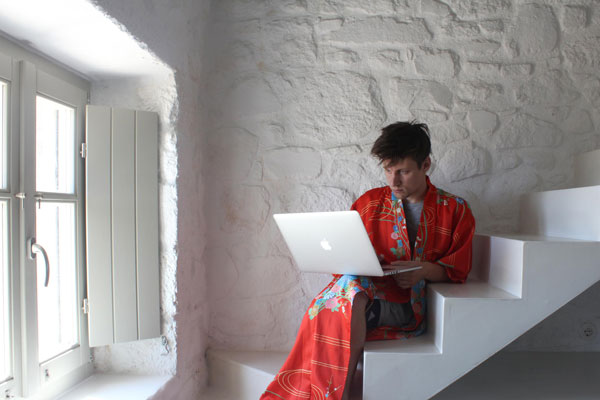άνδρας με κιμονό κάθεται στα σκαλιά έχοντας στα πόδια του ενα macbook