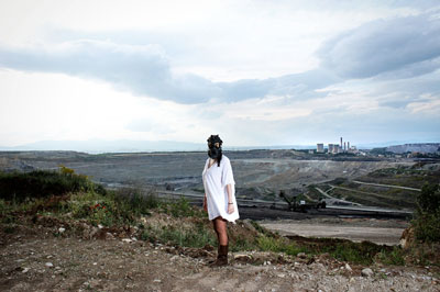 γυναίκα με μάσκα αερίων σε λόφο, εργοστάσιο στο βάθος