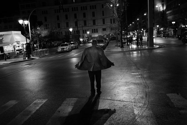 άνδρας περπατάει στο δρόμο με τον αέρα να του παίρνει το σακάκι, ασπρόμαυρη νυχτερινή φωτογραφία