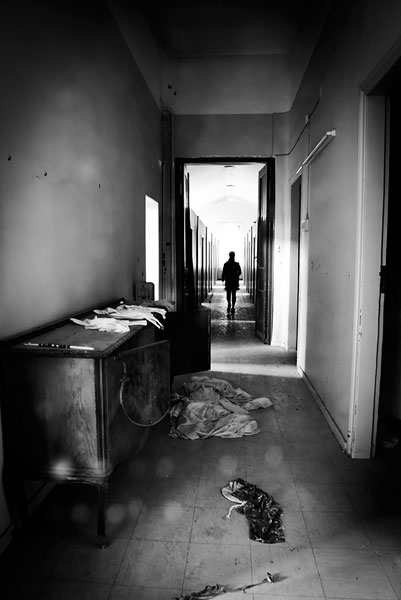 ασπρόμαυρη φωτογραφία, άνδρας περπατάει σε διάδρομο εγκαταλελειμμενου κτηριου