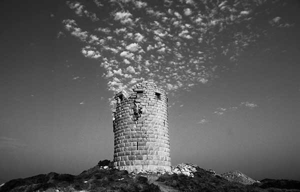 ασπρόμαυρη φωτογραφία ενός πύργου στο Αιγαίο με σύννεφα απο πάνω του