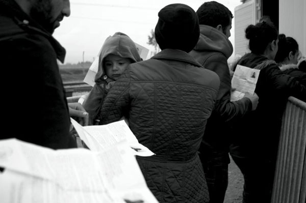 πρόσφυγες κρατάνε στα χέρια τους εγγραφα και ένα παιδάκι