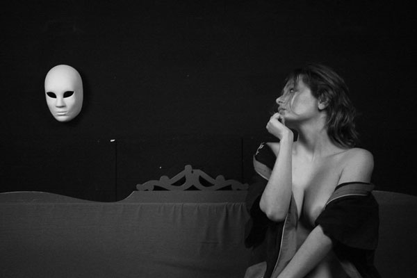 ημιγυμνη γυναίκα κοιτάει μια μάσκα θεάτρου