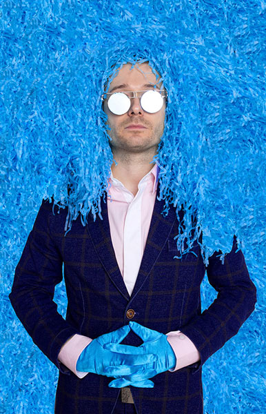 άντρας φοράει μπλε γάντια και άσπρα γυαλιά και έχει καλυμμένο το κεφάλι απο μπλε γκοφρέ χαρτι