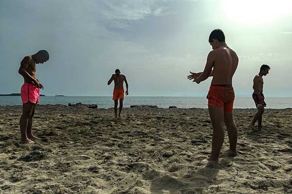 τέσσερις άνδρες με κοντά μαγιό σε παραλία με άμμο καλοκαίρι