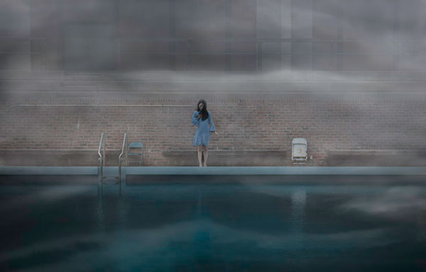 γυναίκα με μπλε φόρεμα στέκεται στην άκρη μιας θερμαινόμενης πισίνας