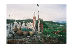 περιφραγμένος χώρος σε κάποιο χωράφι με αγαλματάκια και πύλινες γλάστρες
