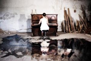 γυναίκα παίζει πιάνο σε έναν εγκαταλελλημενο χώρο