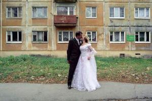 νεόνυμφο ζευγάρι, γαμήλια αναμνηστική φωτογραφία μπροστά από εργατικές κατοικίες