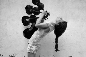 ασπρόμαυρη φωτογραφία, κορίτσι κρατάει 4 βιολιά και χορεύει