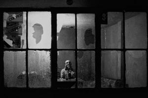 ασπρόμαυρη φωτογραφία, ηλικιωμένος σε κτήριο με σπασμένα παράθυρα