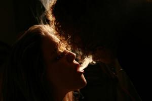 δύο νέα άτομα φυσούν καπνό ο ένας στο στόμα του άλλου