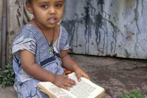 μικρό κορίτσι καθισμένο σε σκαλιά με ένα βιβλίο στα πόδια