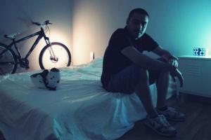 άντρας καθισμένος στο κρεβάτι του, κράνος ποδηλάτου, ποδήλατο