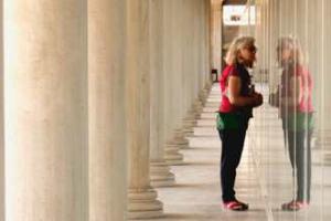 γυναίκα στην είσοδο αρχαιολογικού χώρου κοιτά την αντανάκλαση της στη τζαμαρία