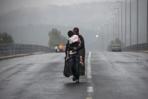 Syrian refugee kisses his daughter as he walks through a rainstorm towards Greece's border with FYROM, near the Greek village of Idomeni