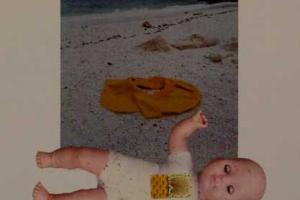 μωρό κούκλα μπροστά σε φωτογραφία παραλίας