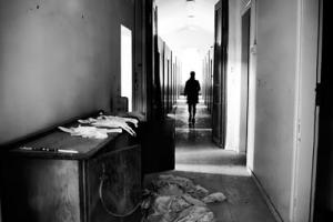 ασπρόμαυρη φωτογραφία, άνδρας περπατάει σε διάδρομο εγκαταλελειμμενου κτηριου