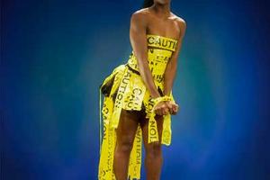 αφροαμερικανή γυναίκα τυλιγμένη με κίτρινη ταινία που γράφει caution πατάει ένα μεγάλο πράσινο φύλλο
