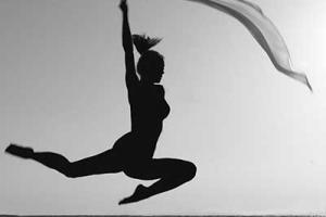 Ασπρόμαυρη φωτογραφία γυναικείας σιλουέτας που χορεύει κρατώντας ένα πέπλο